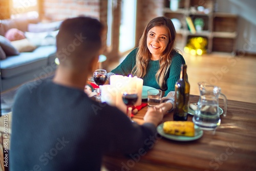 Young beautiful couple smiling happy and confident. Eating food celebrating christmas at home