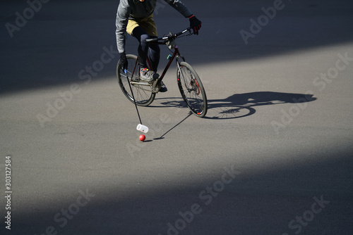 Man plays urban bike polo. Cyclist hits the ball with a bundy, close up photo