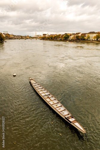 Long Rowing Boat in the Rhine river in Switzerland with Old city center of Basel with Munster cathedral in the background photo