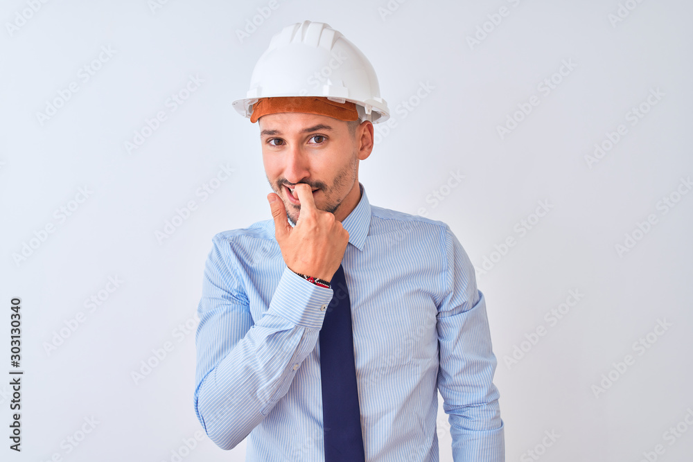 Young business man wearing contractor safety helmet over isolated background looking stressed and nervous with hands on mouth biting nails. Anxiety problem. Young business man wearing contractor safety helmet over isolated background looking stressed and nervous with hands on mouth biting nails. Anxiety problem.