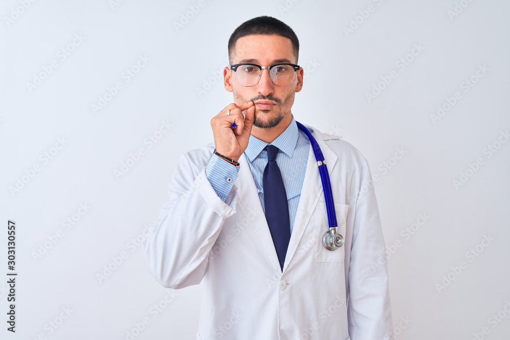 Young doctor man wearing stethoscope over isolated background mouth and lips shut as zip with fingers. Secret and silent, taboo talking Young doctor man wearing stethoscope over isolated background mouth and lips shut as zip with fingers. Secret and silent, taboo talking