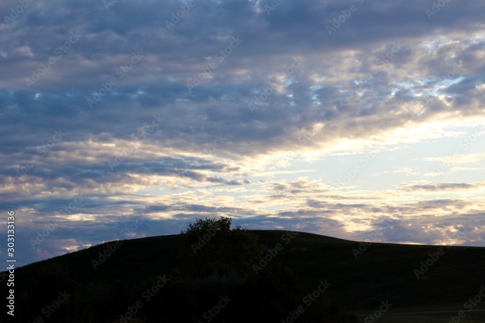 A view of the sunset over the hill in the countryside.