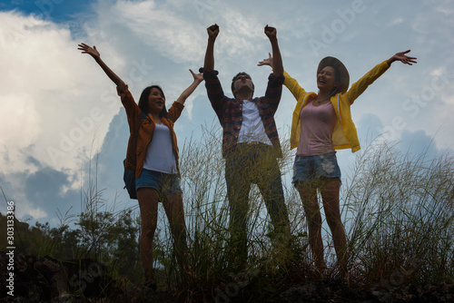 group of young people jumping.Happy family with raised hands enjoying time together on top of the mountain.