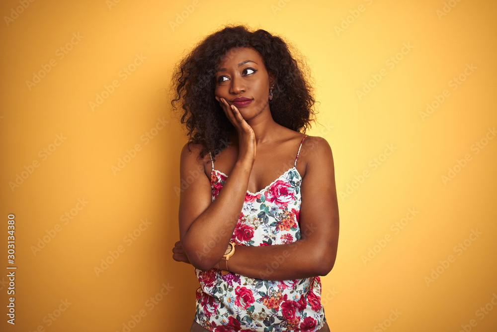 African american woman wearing floral summer t-shirt over isolated yellow background thinking looking tired and bored with depression problems with crossed arms. African american woman wearing floral summer t-shirt over isolated yellow background thinking looking tired and bored with depression problems with crossed arms.
