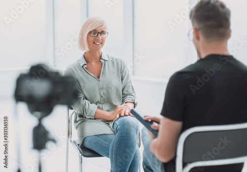 background image of a man and a woman sitting in the Studio during the interview photo