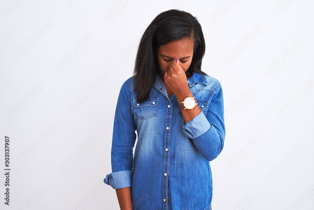 Beautiful young african american woman wearing denim jacket over isolated background tired rubbing nose and eyes feeling fatigue and headache. Stress and frustration concept. Beautiful young african american woman wearing denim jacket over isolated background tired rubbing nose and eyes feeling fatigue and headache. Stress and frustration concept.