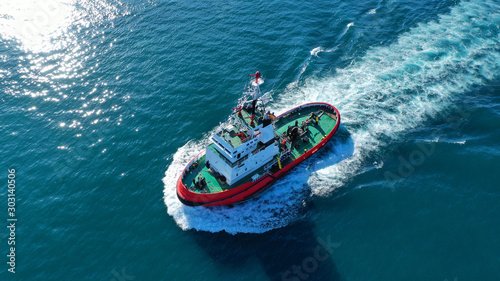 Photography Aerial drone photo of tug boat cruising in high speed near cruise liner docked i