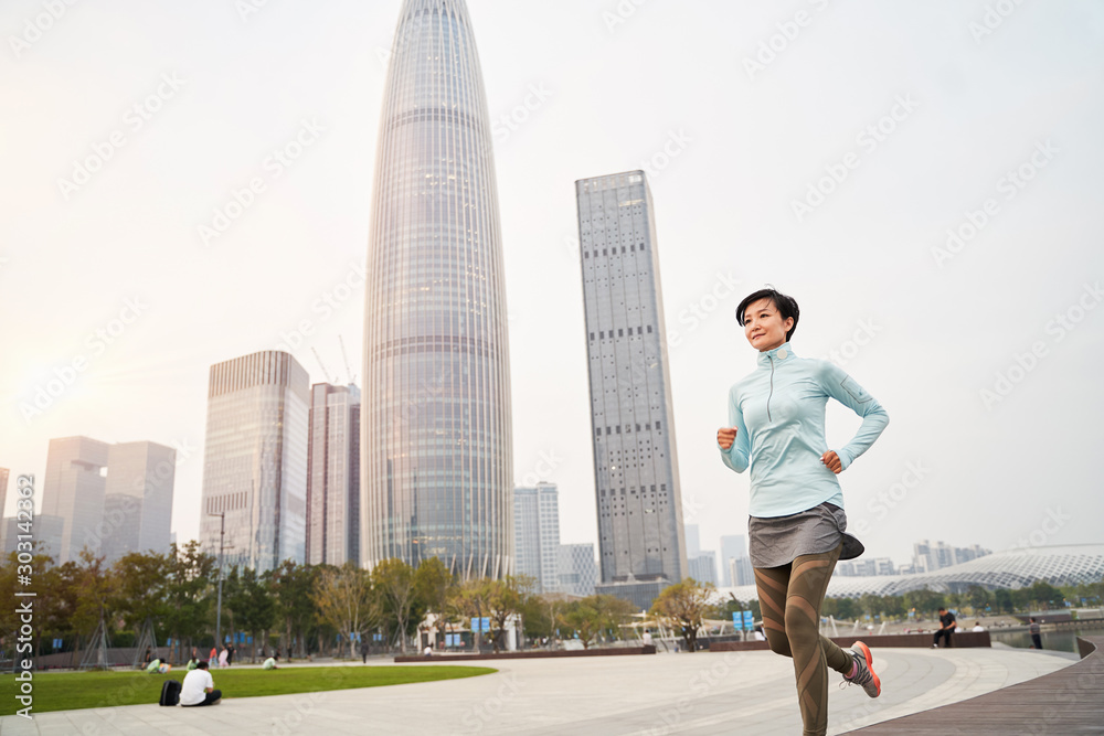 portrait of Asian woman jogging in city park at sunrise