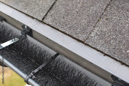 Wallpaper Mural Plastic guard brush in new dark grey plastic rain gutter on asphalt shingles roof. Torontodigital.ca
