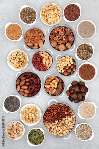 Dried nut and seed collection for vegans and vegetarians, health food high in antioxidants, protein, omega 3. minerals and vitamins. Flat lay on mottled grey background.