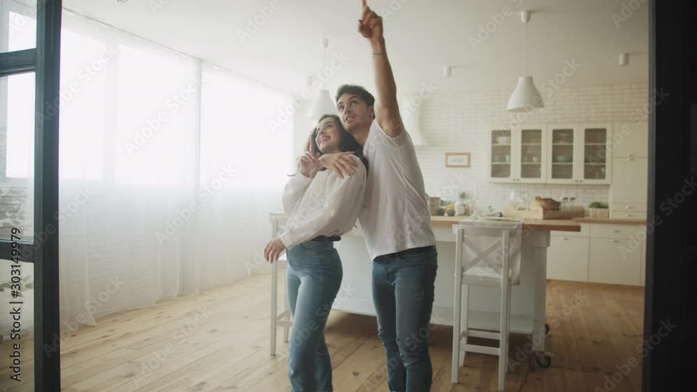 Young couple dreaming new house interior. Family hugging at kitchen.