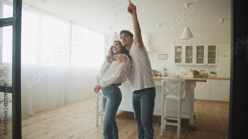 Young couple dreaming new house interior. Family hugging at kitchen. photo