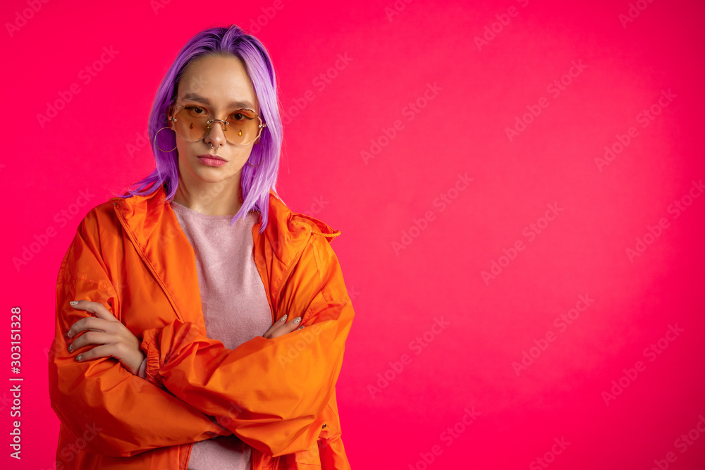 Portrait of cheerful unusual girl with violet hairstyle isolated in studio. Trendy woman with nose piercing, sunglasses. Vibrant colorful shot.