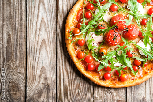 Traditional italian pizza with cherry tomatoes on a light wooden background top view copy space.