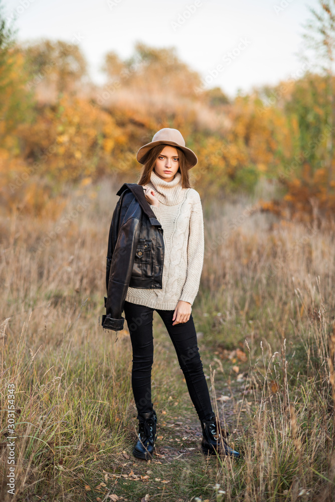 Portrait of beautiful woman sitting on the wooden stairway. Fashion outdoor shot of lady in cozy clothes and straw hat enjoying nature views in autumn countryside Portrait of beautiful woman sitting on the wooden stairway. Fashion outdoor shot of lady in cozy clothes and straw hat enjoying nature views in autumn countryside
