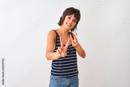 Young beautiful woman wearing striped t-shirt standing over isolated white background smiling looking to the camera showing fingers doing victory sign. Number two.