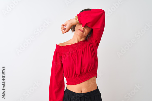 Young beautiful woman wearing red summer t-shirt standing over isolated white background covering eyes with arm, looking serious and sad. Sightless, hiding and rejection concept © Krakenimages.com