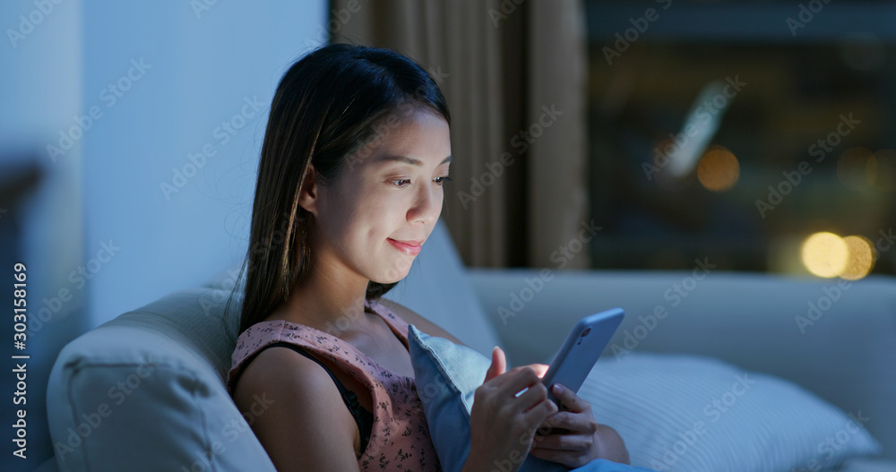 Woman look at cellphone at home in the evening Woman look at cellphone at home in the evening