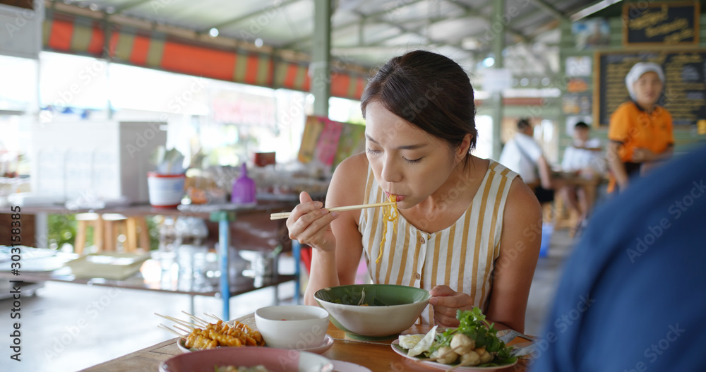 Woman eat boat noodles at outdoor street vendor in Thailand Woman eat boat noodles at outdoor street vendor in Thailand