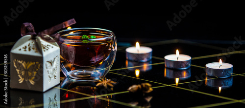 tea with cinnamon in a transparent glass and candles