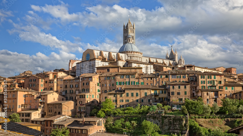 Old houses in historic centre in Siena. The Duomo Santa Maria Assunta (Cathedral of Siena) is located on the highest point of the city hillin Siena, Tuscany, Italy