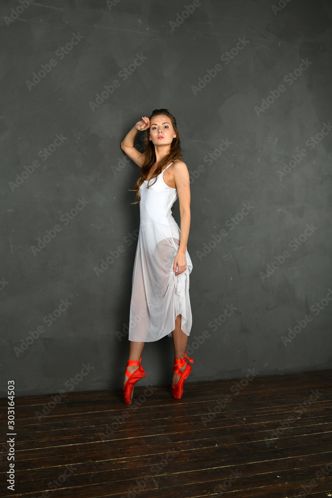girl in a white translucent dress in red pointes on a gray background girl in a white translucent dress in red pointes on a gray background