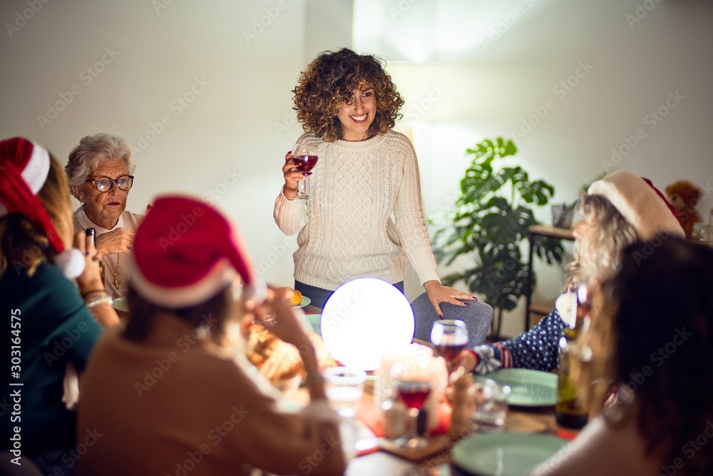 Beautiful group of women smiling happy and confident. On of them holding cup of wine speaking speech celebrating christmas at home