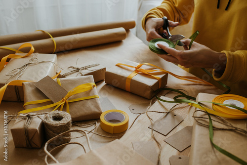 Woman packaging box. Kraft wrapping paper and natural twine. Recycling material. Happy holiday present, surprise. Gifts for boxing day. Delivery service, shipping. Handwork art craft. Celebration