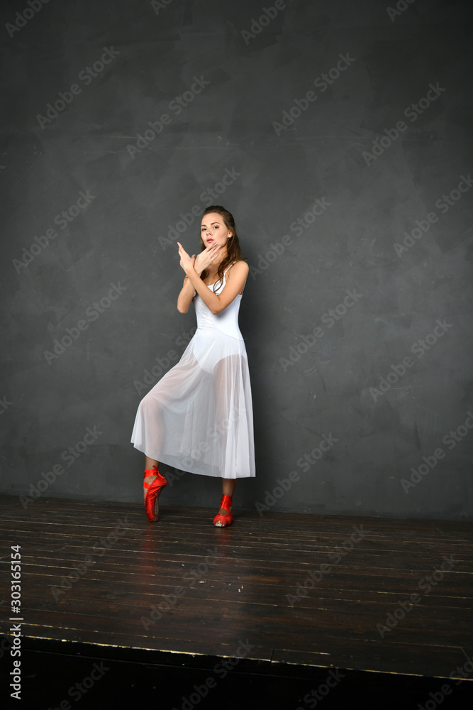 girl in a white translucent dress in red pointes on a gray background girl in a white translucent dress in red pointes on a gray background