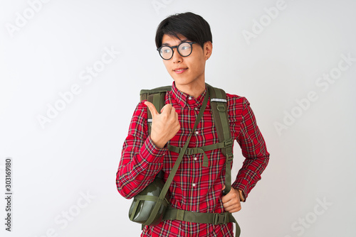 Chinese hiker man wearing backpack canteen glasses over isolated white background smiling with happy face looking and pointing to the side with thumb up.