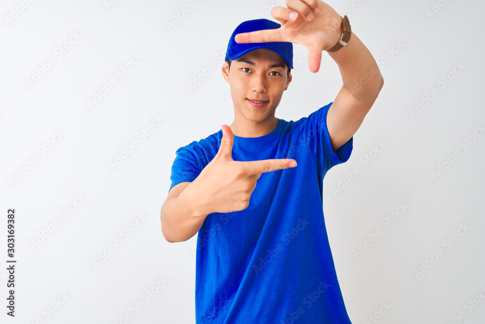 Chinese deliveryman wearing blue t-shirt and cap standing over isolated white background smiling making frame with hands and fingers with happy face. Creativity and photography concept. Chinese deliveryman wearing blue t-shirt and cap standing over isolated white background smiling making frame with hands and fingers with happy face. Creativity and photography concept.