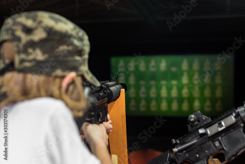 Little boy aiming gun at target in shooting range