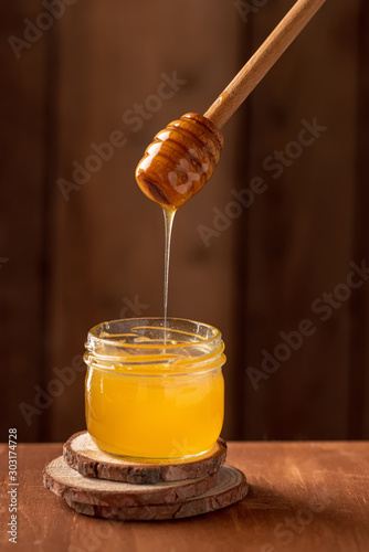 jar with honey on a wooden background with a spoon