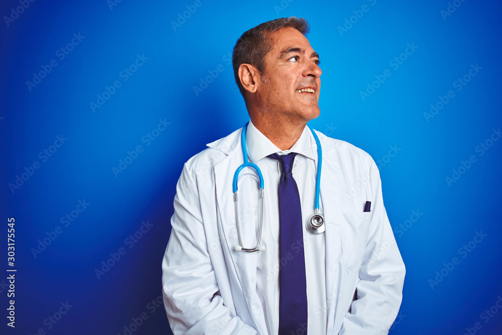 Handsome middle age doctor man wearing stethoscope over isolated blue background looking away to side with smile on face, natural expression. Laughing confident. Handsome middle age doctor man wearing stethoscope over isolated blue background looking away to side with smile on face, natural expression. Laughing confident.