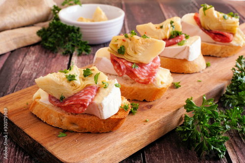 Foto Crostini appetizers with brie cheese, salami and artichokes