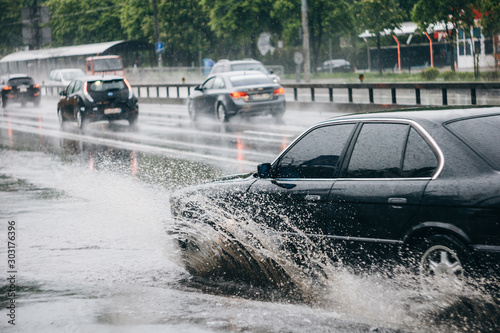 Ukraine. Kiev - 05 12 2019 Spraying water from the wheels of a vehicle moving on a wet city asphalt road. The wet wheel of a car moves at a speed along a puddle on a flooded city road during rain.