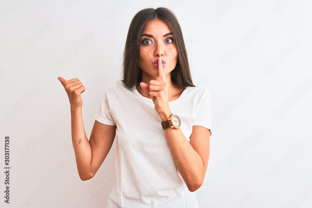 Young beautiful woman wearing casual t-shirt standing over isolated white background asking to be quiet with finger on lips pointing with hand to the side. Silence and secret concept. Young beautiful woman wearing casual t-shirt standing over isolated white background asking to be quiet with finger on lips pointing with hand to the side. Silence and secret concept.