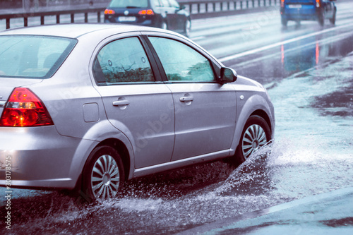 Ukraine. Kiev - 05,12,2019 Spraying water from the wheels of a vehicle moving on a wet city asphalt road. The wet wheel of a car moves at a speed along a puddle on a flooded city road during rain.