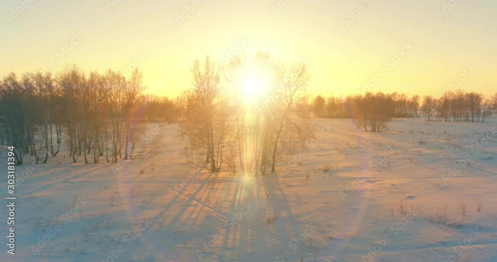 Aerial drone view of cold winter landscape with arctic field, trees covered with frost snow and morning sun rays over horizon. Aerial drone view of cold winter landscape with arctic field, trees covered with frost snow and morning sun rays over horizon.