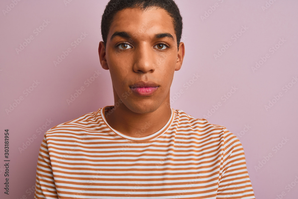 Young handsome arab man wearing striped t-shirt standing over isolated pink background with a confident expression on smart face thinking serious Young handsome arab man wearing striped t-shirt standing over isolated pink background with a confident expression on smart face thinking serious