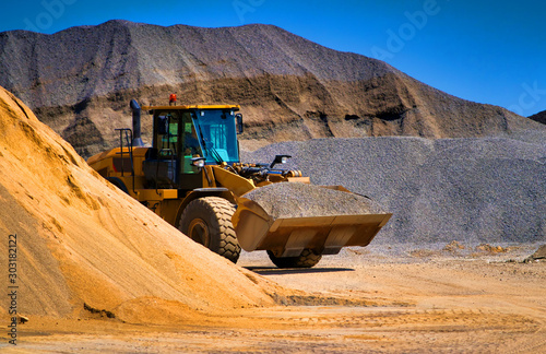 Sand quarry, excavating equipment, bulldozer with heap of sand in background. Selective focus.