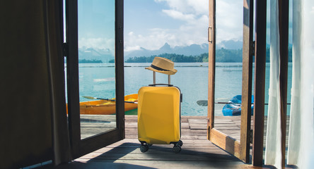 Travel suitcase with hat at house on the lake, summer beach vacation concept. 