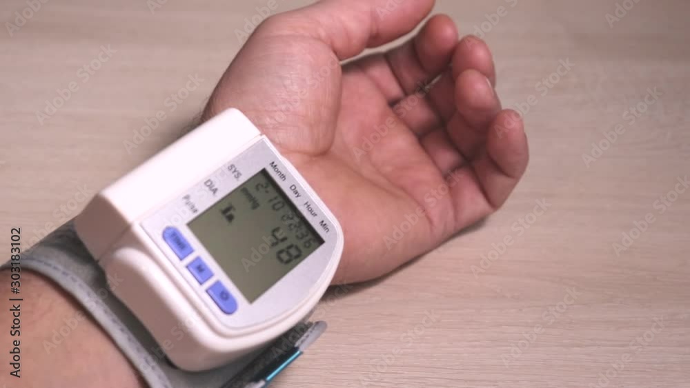 Age-related pressure control. Pressure measurement with an automatic tonometer on the wrist. Hand with a working tonometer on the table. Age-related pressure control. Pressure measurement with an automatic tonometer on the wrist. Hand with a working tonometer on the table.