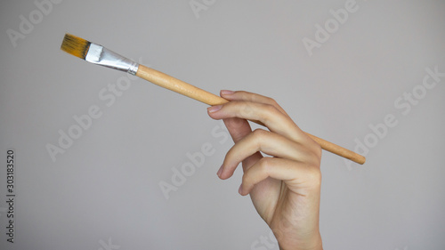 Woman's hand with a brush over a grey empty background.