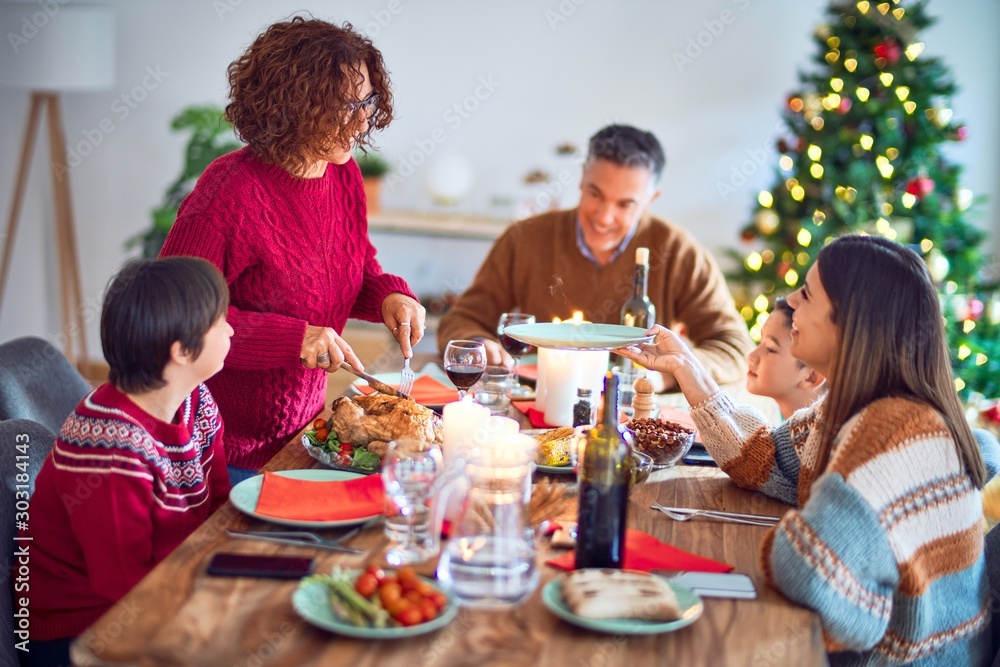 Beautiful family smiling happy and confident. One of them curving roasted turkey celebrating christmas at home