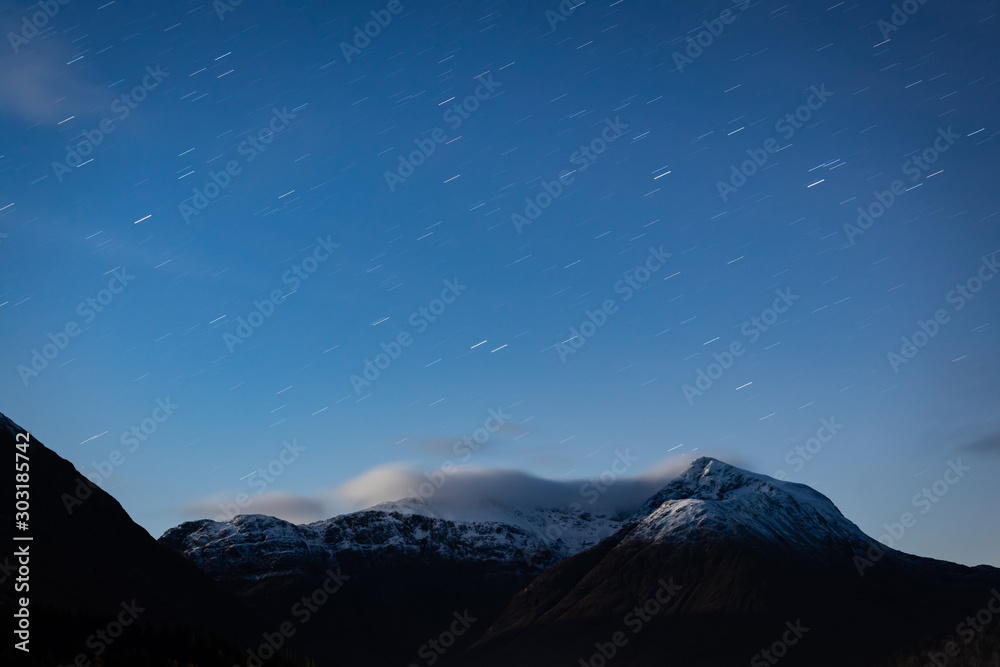 the night sky above buachaille etive mor and surrounding mountains of glencoe in the argyll region of the highlands of scotland during a clear dark sky night in autumn