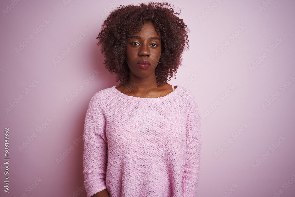 Young african afro woman wearing sweater standing over isolated pink background Relaxed with serious expression on face. Simple and natural looking at the camera. Young african afro woman wearing sweater standing over isolated pink background Relaxed with serious expression on face. Simple and natural looking at the camera.