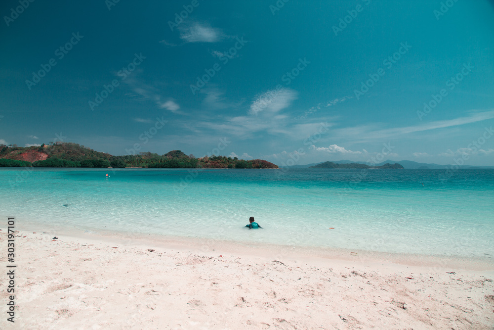 A kid playing in shallow part of a quiet beach in Mahitam Island, Lampung A kid playing in shallow part of a quiet beach in Mahitam Island, Lampung