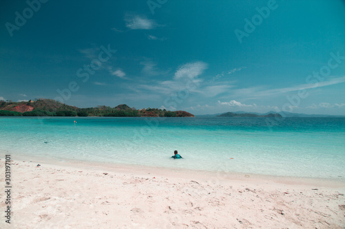 A kid playing in shallow part of a quiet beach in Mahitam Island, Lampung