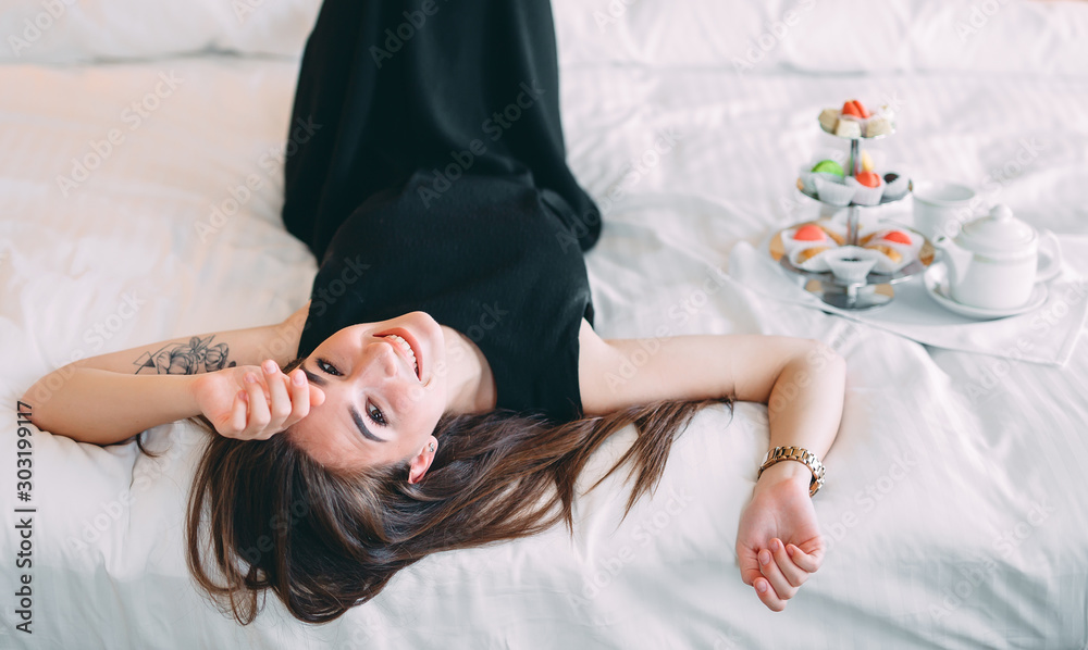 The girl is lying on the bed in a hotel room or at home.